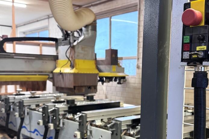 CNC-Fräse in einer Werkstatt mit Steuerkonsole und Sicht auf Maschinen im Hintergrund.