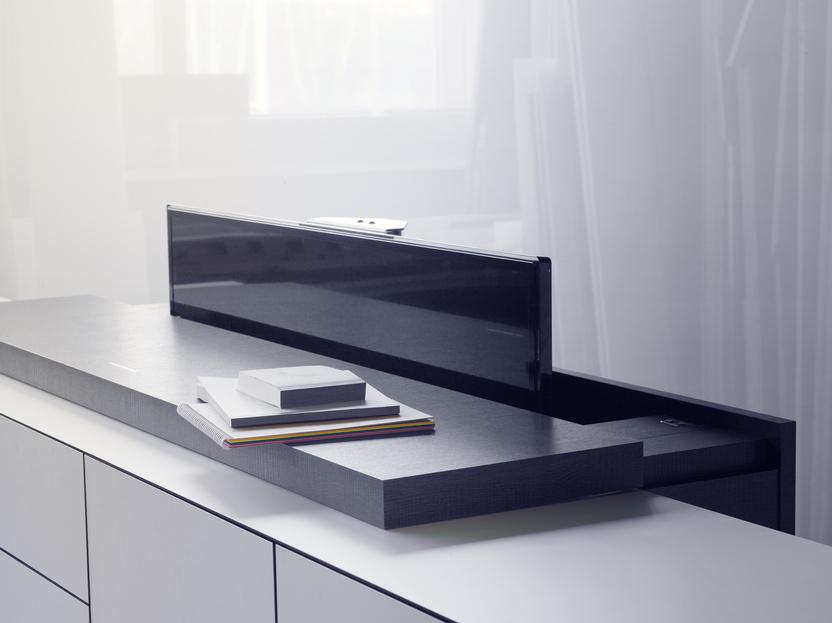 Moderne Möbelanordnung mit einem schwarzen Sichtschutz auf einer Holzoberfläche und gestapelten Notizblöcken.