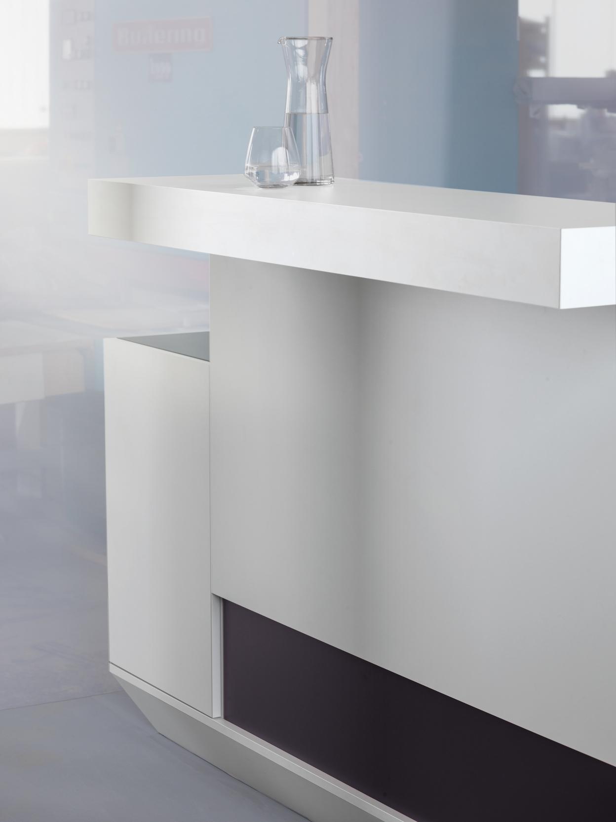 Moderne Bar mit einem weißen Tisch und einer Glaskaraffe sowie einem Glas auf der Oberfläche. Minimalistisches Design.