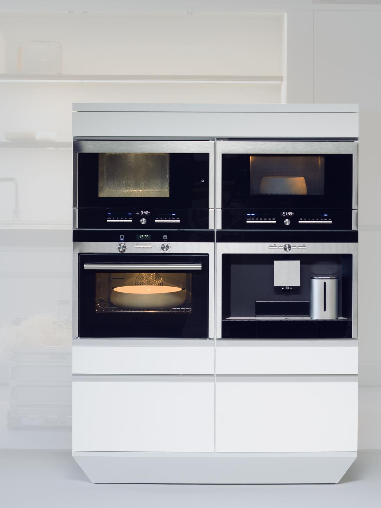 Moderne Kücheneinheit mit vier integrierten Geräten: Mikrowelle, Dampfgarer, Backofen und Kaffeevollautomat.