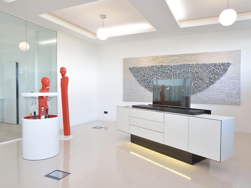Moderne Wohnraum mit einer weißen Anrichte, einem Fernseher und roter Skulptur neben einem Gemälde auf der Wand.