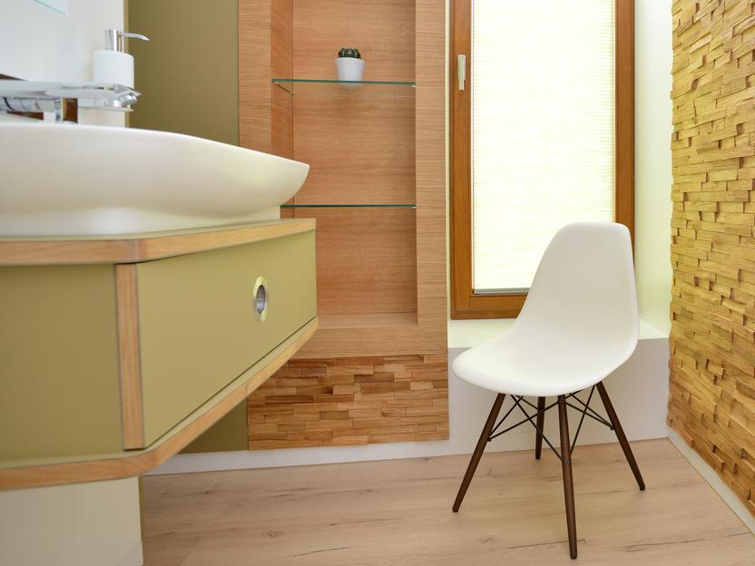 Helles Badezimmer mit Holzregal, Waschtisch und moderner weißer Stuhlwand. Fenster mit Jalousien sorgt für Tageslicht.