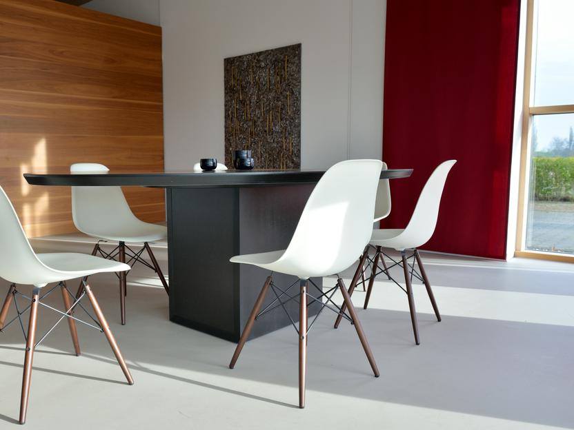 Moderne Essgruppe mit einem schwarzen Tisch und vier weißen Stühlen in einem hellen Raum mit großen Fenstern.