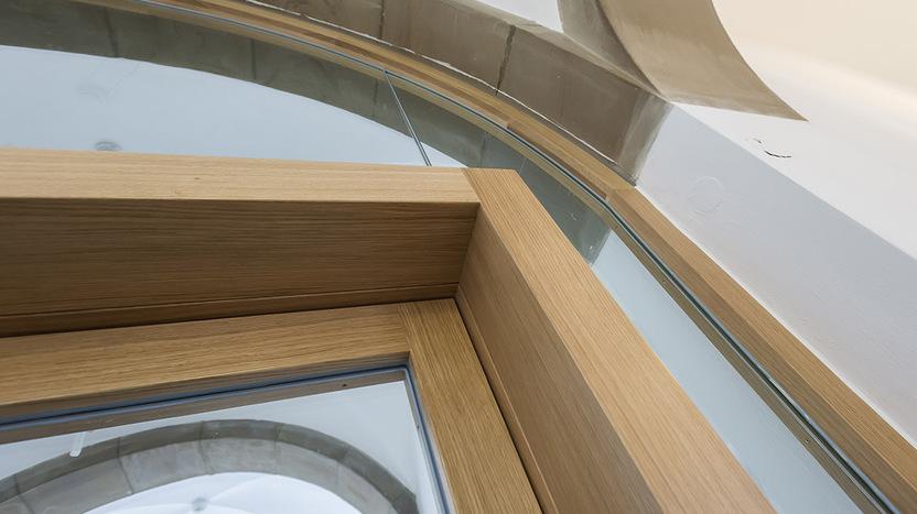 Detailaufnahme einer modernen Fensterkonstruktion aus Holz und Glas mit gewölbter Form.