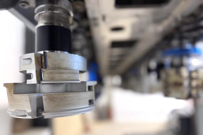 Nahaufnahme eines Maschinenfräswerkzeugs mit abgerundeten Kanten unter einer Maschinenstruktur.