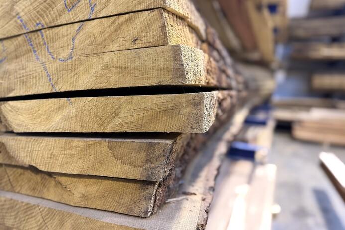 Nahaufnahme von gestapelten Holzbrettern mit sichtbaren Fugen und strukturierten Oberflächen in einem Holzlager.