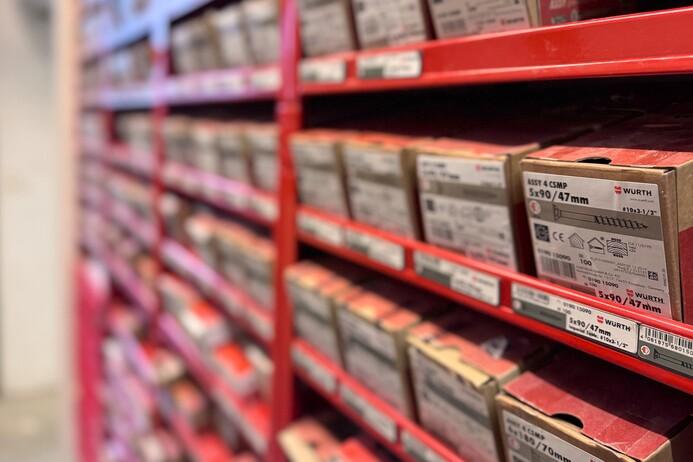 Regal mit zahlreichen Verpackungen von Befestigungselementen in verschiedenen Größen und Farben.