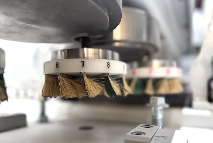 Nahaufnahme von rotierenden Bürsten an einer Maschinenvorrichtung zur Oberflächenbearbeitung.